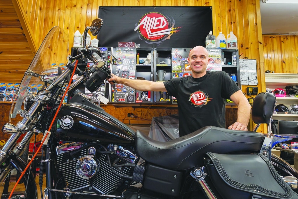 Danny Room stands with the Harley-Davidson Dyna Street Bob that he was readying for a customer. Reflecting on the difference between biking culture in the U.S. and his native Britain, Room said that open space and sunnier weather make for a longer riding season here. U.S. riders, he said, are more lax about wearing protective gear. “I wear full protective gear all the time,” he said. “I value my skin.”